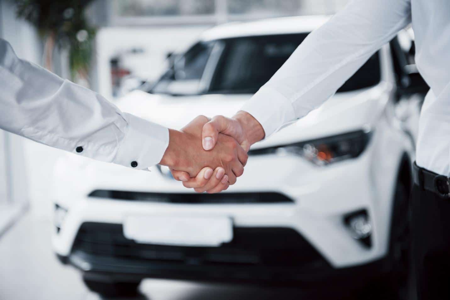 A close-up of a handshake in front of a car
AI-generated content may be incorrect.